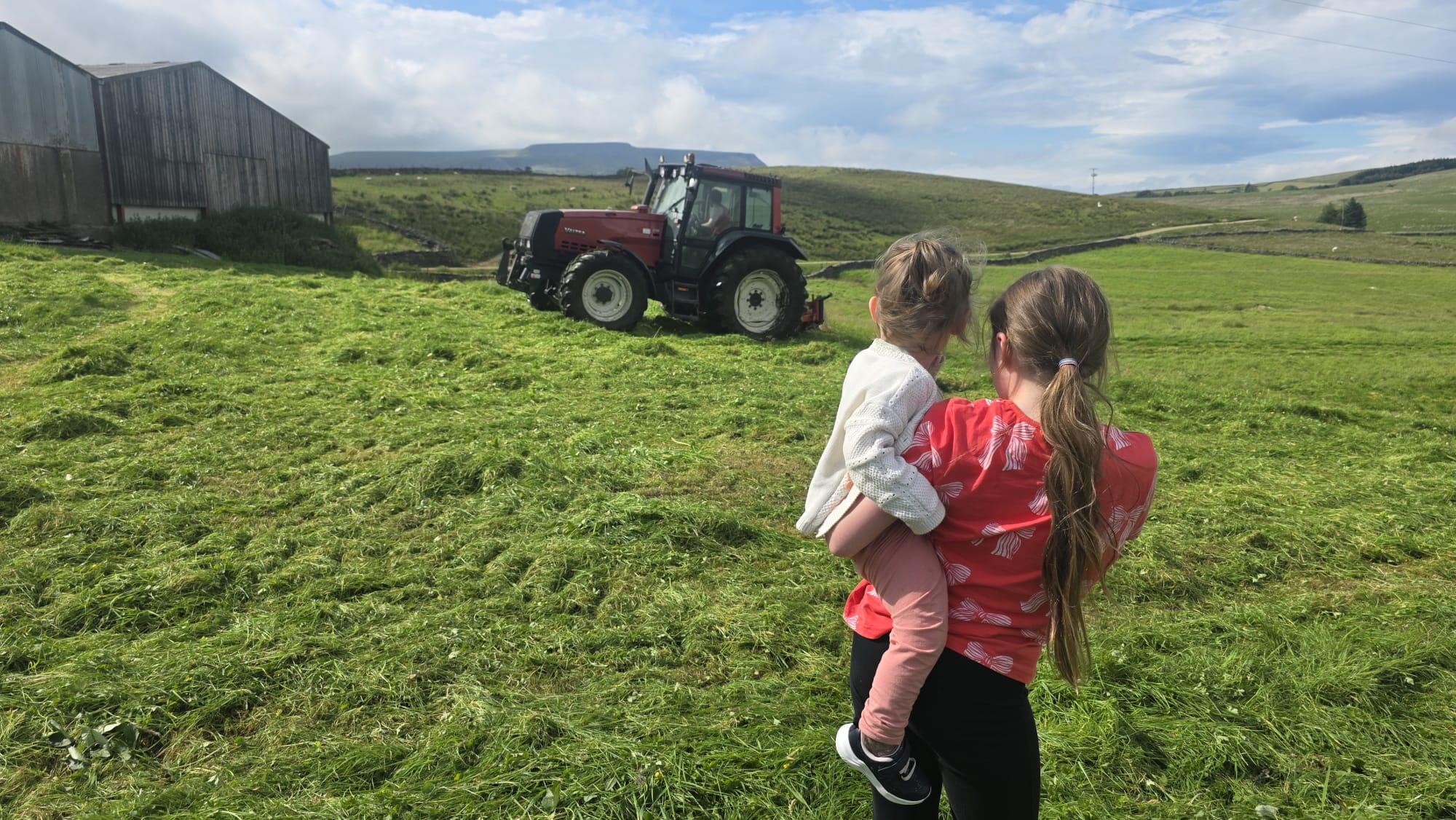 Family watching the tractor at work on the hill farm